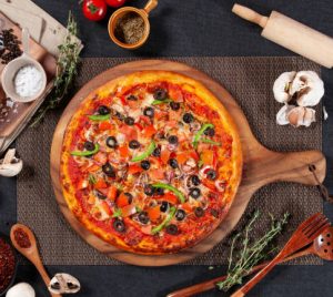 Vegetable Lover Pizza with tomato, onion, chili powder, garlic, and black pepper isolated on wooden cutting board side view of fastfood on wooden table